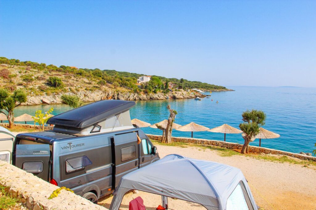 Camper van by serene Adriatic beach, sunny day in Novalja, Croatia.